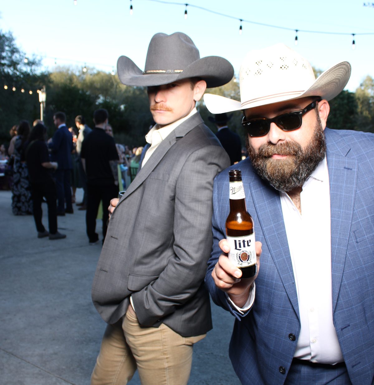 Two guests in cowboy hats striking a pose at an outdoor event
