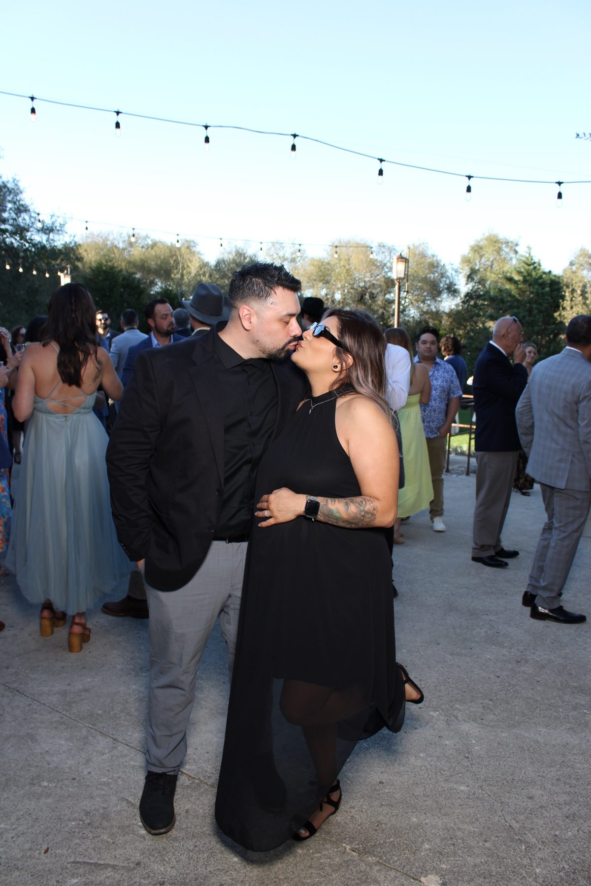 Couple sharing a kiss at an outdoor Austin wedding under string lights